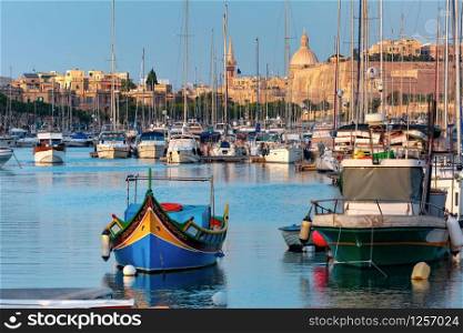 Valletta harbour with yachts and multicolored fishing boats Luzzu with eyes, church and fortress, illuminated by sunset light, Malta. Valletta Skyline from Sliema at sunset, Malta