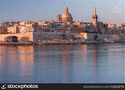 Valletta with Our Lady of Mount Carmel church and St. Paul&rsquo;s Anglican Pro-Cathedral at sunrise as seen from Sliema, Valletta, Malta. Valletta Skyline from Sliema at sunset, Malta