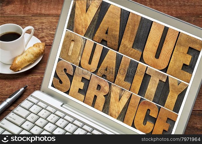 value, quality, service - business mantra or motto concept - words in vintage letterpress wood type on a laptop screen with a cup of coffee