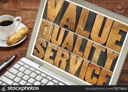 value, quality, service - business mantra or motto concept - words in vintage letterpress wood type on a laptop screen with a cup of coffee