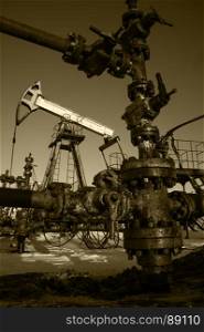 Valve, pipe and oil pump. Oilfield, petroleum industrial site. Toned sepia.