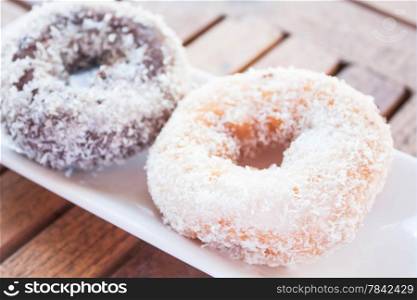 Vanilla and chocolate coconut donuts on wooden table, stock photo