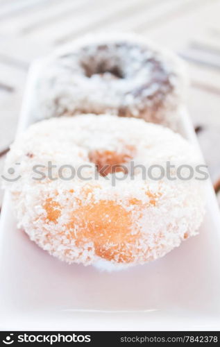 Vanilla and chocolate coconut donuts serving on white plate, stock photo