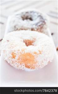 Vanilla and chocolate coconut donuts serving on white plate, stock photo