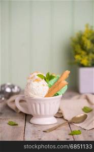 Vanilla and mint ice cream in cup on wooden vintage style background.