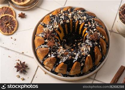 Vanilla bundt cake with chocolate glaze and nuts on top, top view. Vanilla bundt cake