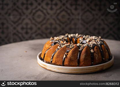 Vanilla bundt cake with chocolate glaze and nuts on top. Vanilla bundt cake