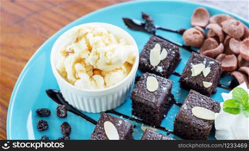Vanilla ice-cream and brownies on a blue plate.