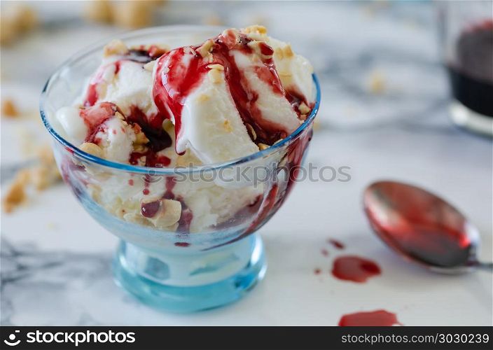 Vanilla ice cream in blue bowl,on white background,top view. Vanilla ice cream in blue bowl,on white background,top view,nuts and berry syrup over ice cream.