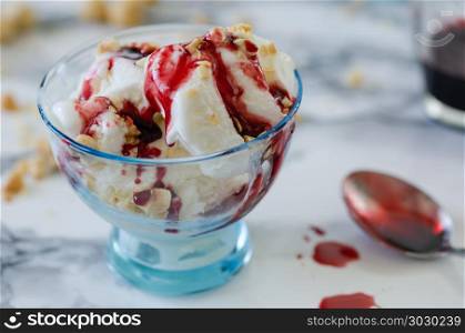 Vanilla ice cream in blue bowl,on white background,top view. Vanilla ice cream in blue bowl,on white background,top view,nuts and berry syrup over ice cream.