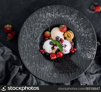 Vanilla ice cream scoops with fresh berries on black plate