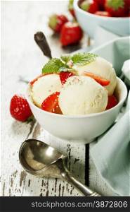 Vanilla ice cream with fresh strawberry in white cup on wooden background