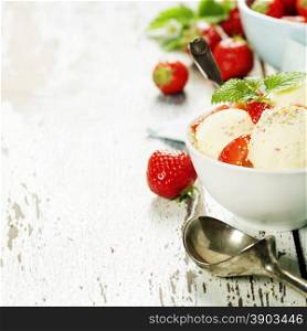 Vanilla ice cream with fresh strawberry in white cup on wooden background