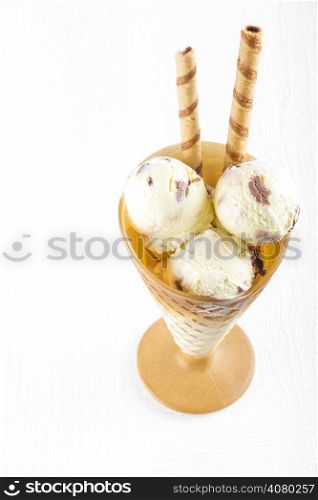 Vanilla ice cream with wafer in cup on white wooden background