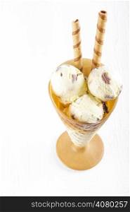 Vanilla ice cream with wafer in cup on white wooden background