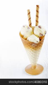 Vanilla ice cream with wafer in cup on white wooden background