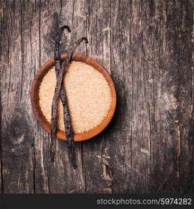 Vanilla sugar in a wooden bowl on a rustic background. Two vanilla pods on brown sugar. Vanilla sugar