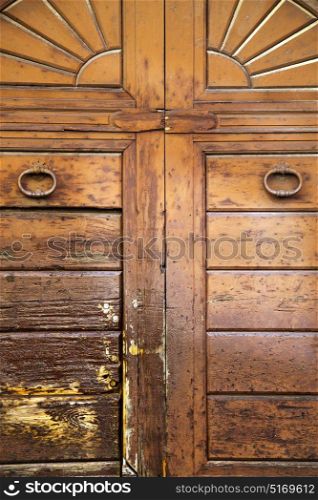 varese abstract rusty brass brown knocker in a closed wood door vedano olona italy