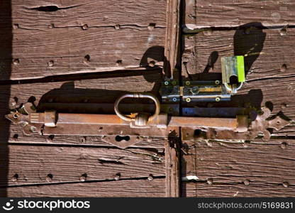 varese abstract rusty brass brown knocker in a door curch closed wood lombardy italy sumirago