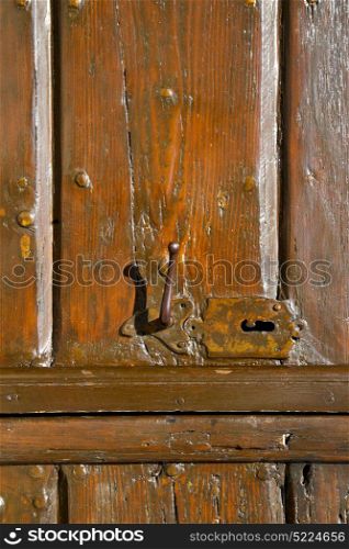 varese sumirago abstract rusty brass brown knocker in a door curch closed wood lombardy italy