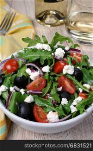 Variation of Greek salad with arugula, cherry slices, feta and olives