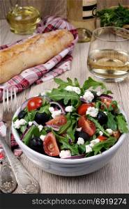 Variation of Greek salad with arugula, cherry slices, feta and olives