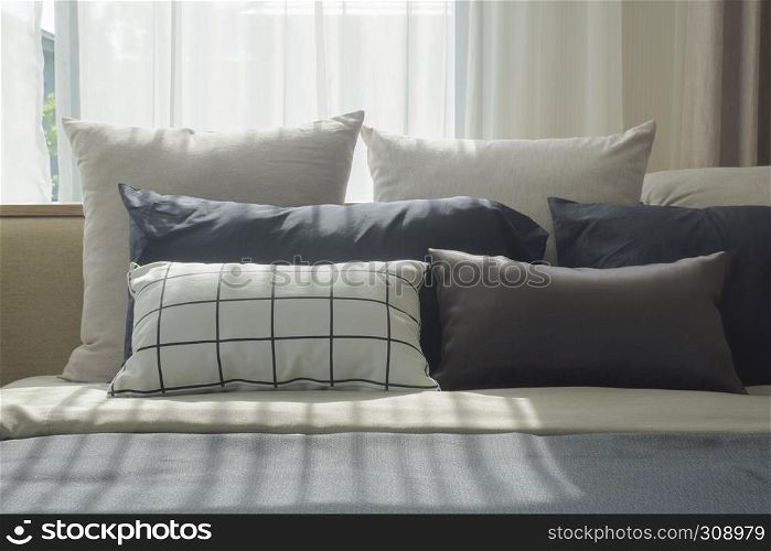 Varies size of pillows setting on bed with natural light in bedroom