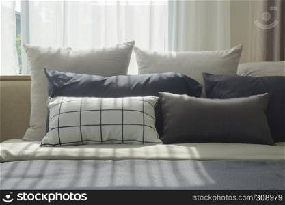 Varies size of pillows setting on bed with natural light in bedroom
