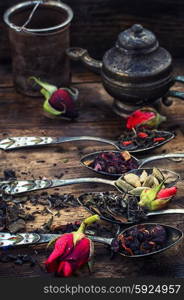 Varieties of dry tea. Dried tea leaves in spoons on stylish background of the teapot.