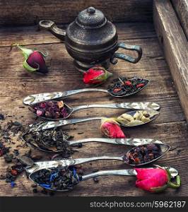 Varieties of dry tea. Varieties of tea brewed in an iron spoon on the background of symbolic teapot