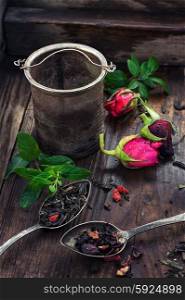 Varieties of tea brewing. Dry tea leaves in spoons with small buds of roses in wooden box