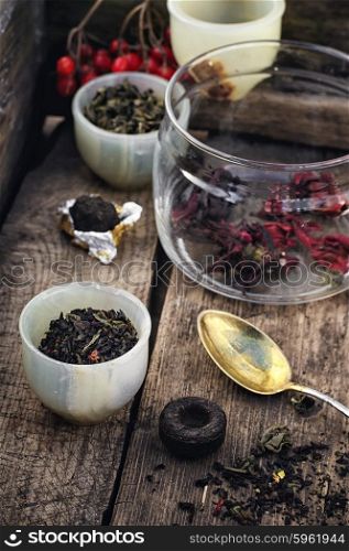 Varieties of tea. small cup with tea brewing in the background spoons and viburnum