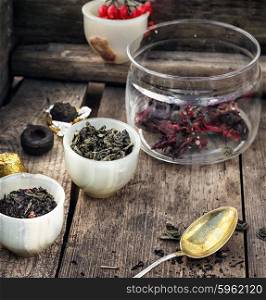 Varieties of tea. small cup with tea brewing in the background spoons and viburnum