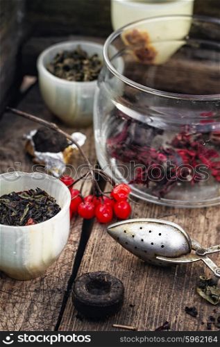 Varieties of tea. trendy cup with tea brewing in the background spoons and viburnum