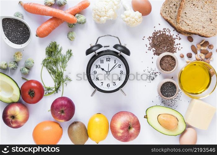 variety ingredients with alarm clock arranged against isolated white background