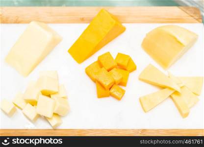 Variety of cheese on rustic wooden table in buffet line