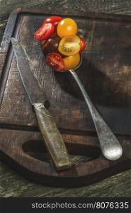 Variety of cherry tomatoes in spoon on wood