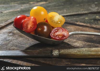 Variety of cherry tomatoes in spoon on wood