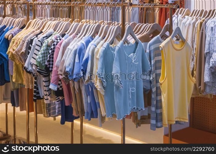 Variety of children clothes hanging on clothing racks for sale in fashion store at shopping mall