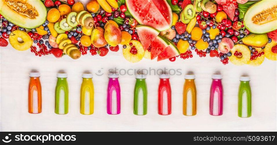 Variety of colorful smoothies and juices beverages in bottles with various fresh organic fruits and berries ingredients on white wooden background, top view. Healthy food concept