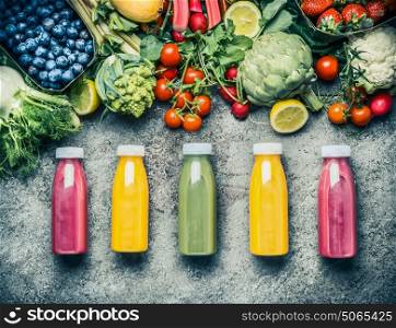 Variety of colorful Smoothies or juices bottles beverages drinks with various fresh ingredients: fruits ,berries and vegetables on gray concrete background , top view. Healthy Food concept
