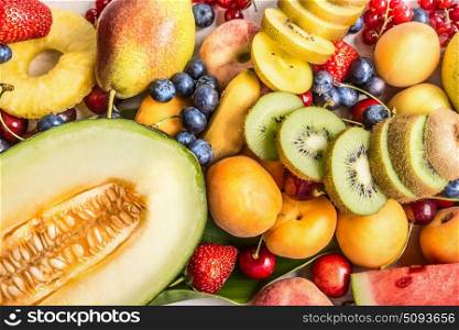 Variety of colorful summer fruits background: melon, sliced kiwi,banana, Peach, strawberry, pineapple, cherry, apricot, top view