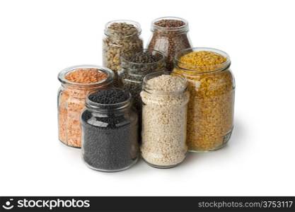 Variety of dried lentils in glass pots on white background