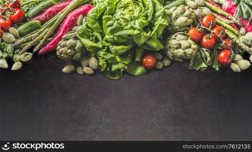 Variety of farm vegetables: lettuce , green almonds, asparagus,artichoke, radishes and cherry tomatoes on dark background. Healthy clean vegetarian food and eating concept. Top view. Frame