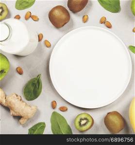 Variety of fresh fruits and nuts for healthy eating or making green smoothie over light grey background, top view. Healthy eating, vitamin, detox, diet food, clean eating concept