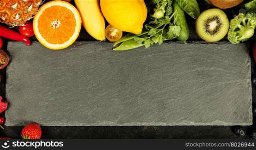 Variety of fresh raw organic fruits and vegetables with cutting board -