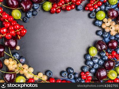 Variety of fresh summer berries on chalkboard background, top view, frame, horizontal