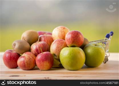 variety of fruits and a shopping cart on a wooden table, outdoor