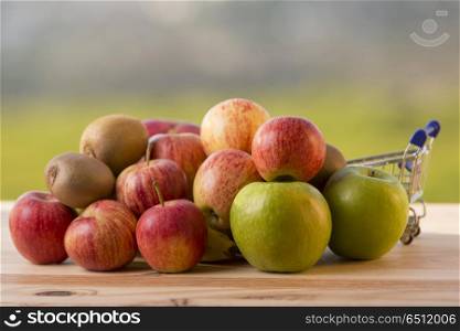 variety of fruits and a shopping cart on a wooden table, outdoor. variety of fruits