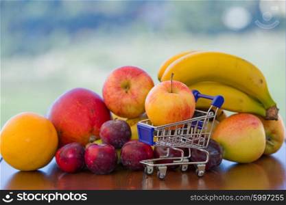 variety of fruits and a small shopping cart on table in the garden